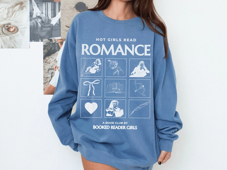 Puede incluir: Una sudadera azul con el texto "HOT GIRLS READ ROMANCE" y una cuadr&iacute;cula de nueve ilustraciones blancas, que incluyen un coraz&oacute;n, un lazo, un libro, una flecha, una pluma y una persona leyendo. El texto "A BOOK CLUB BY BOOKED READER GIRLS" est&aacute; impreso debajo de la cuadr&iacute;cula.