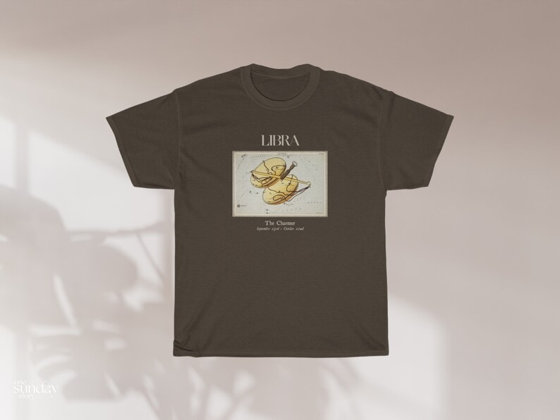 May include: A dark brown t-shirt featuring a Libra zodiac design. The graphic includes the word "LIBRA" above an illustration of the scales, with text below indicating the dates September 23 - October 22.