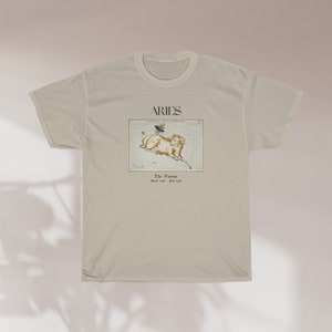 Pu&ograve; includere: Una t-shirt beige con una stampa grafica della costellazione dell'Ariete. La grafica include il testo "Aries" e "The Ram" con le date dal 21 marzo al 19 aprile.