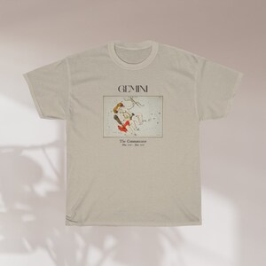 Pode incluir: Uma camiseta bege com uma estampa gr&aacute;fica da constela&ccedil;&atilde;o de G&ecirc;meos. O texto "GEMINI" e "The Communicators" est&aacute; impresso na camiseta.