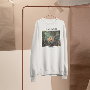 May include: White sweatshirt with a painting of a couple on a swing by Jean-Honor&eacute; Fragonard. The painting is titled "The Swing" and the year 1767 is printed below it.