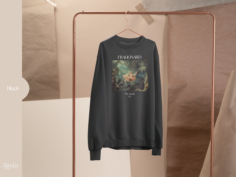 May include: A dark gray sweatshirt with a print of a painting by Fragonard. The painting depicts a woman in a white dress sitting on a swing. The text "The Swing" and "1767" are printed below the painting.