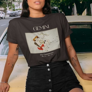 Pode incluir: Camiseta preta com um gr&aacute;fico da constela&ccedil;&atilde;o de G&ecirc;meos e o texto "GEMINI The Communicator May 21st - June 21st"