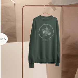 May include: Forest green sweatshirt with a white floral design and the text "One love in forever, adorned with sweet little things, from the garden of my soul, 1975".