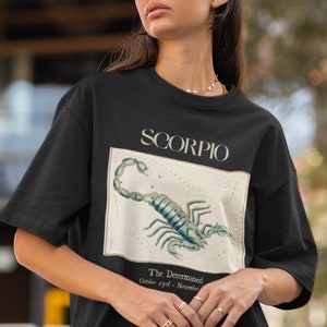 Op de afbeelding: Zwart T-shirt met een vintage illustratie van het sterrenbeeld Schorpioen en de tekst "Scorpio, The Determined, October 23rd - November 21st".