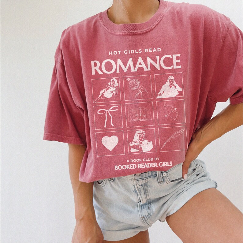 May include: A red t-shirt with the text "HOT GIRLS READ ROMANCE" and a graphic of nine squares with different images. The text "A BOOK CLUB BY BOOKED READER GIRLS" is below the graphic.