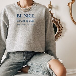 May include: A gray sweatshirt with the text "BE NICE. Get Lots Of Sleep. Drink Plenty Of Water." printed in blue.