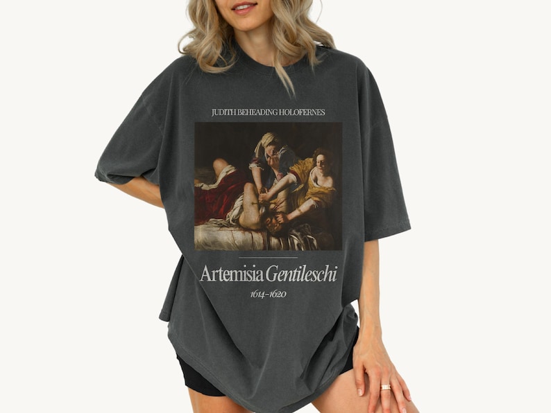 May include: A dark gray t-shirt with a painting of Judith Beheading Holofernes by Artemisia Gentileschi (1614-1652).