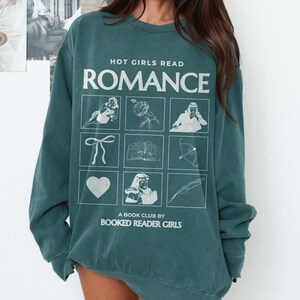 Puede incluir: Sudadera de color verde azulado con el texto "HOT GIRLS READ ROMANCE" y un gr&aacute;fico de nueve cuadrados con diferentes ilustraciones. El texto debajo del gr&aacute;fico dice "A BOOK CLUB BY BOOKED READER GIRLS".