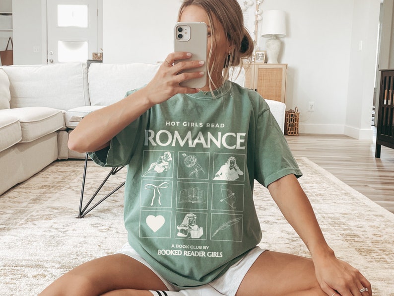 May include: A green t-shirt with the text "Hot Girls Read Romance" and a graphic of nine squares with different images. The text "A Book Club by Booked Reader Girls" is at the bottom of the shirt.