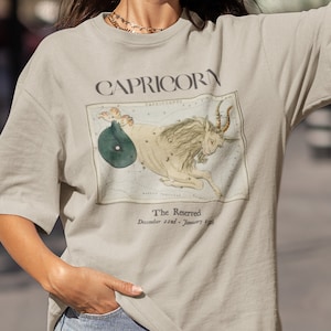May include: A beige t-shirt with a vintage illustration of the Capricorn constellation and the text "Capricorn The Reserved December 22nd - January 19th".