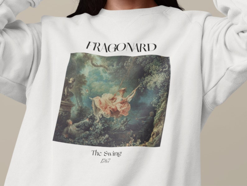 May include: White sweatshirt with a print of a painting by Jean-Honor&eacute; Fragonard called "The Swing" from 1767. The painting depicts a woman on a swing in a lush garden setting.