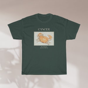 May include: A dark green t-shirt with a vintage illustration of the Cancer zodiac sign, a crab, and the text "Cancer, The  Nurturer, June 21st - July 22nd".