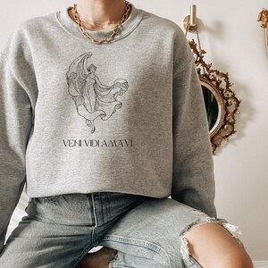 May include: Gray sweatshirt with a black and white illustration of a woman with wings and the text "VENI VIDI AMAVI".