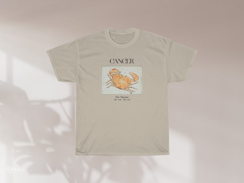 May include: A beige t-shirt with a graphic of a crab and the text "Cancer The Narcissist June 21st - July 22nd".