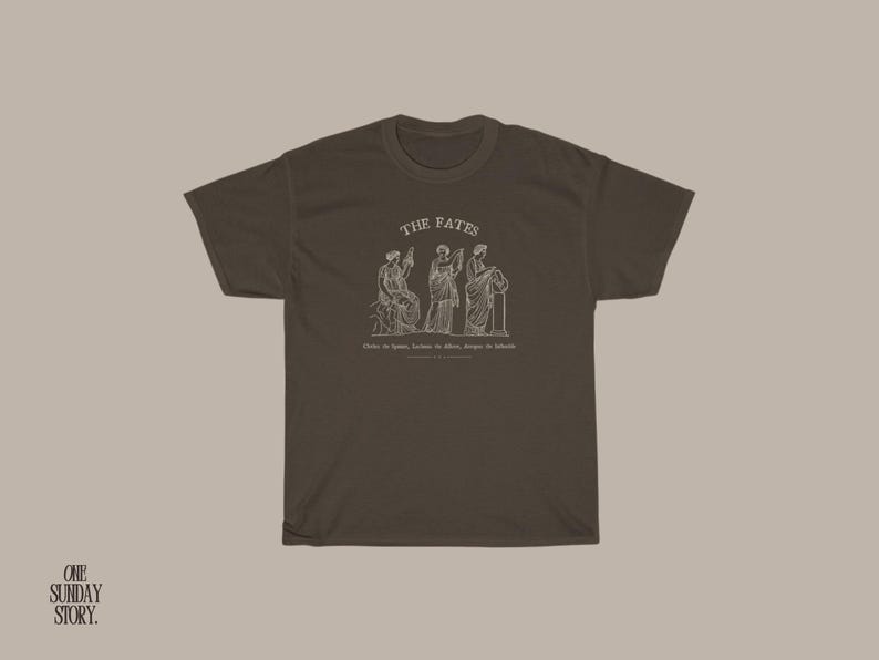 May include: A brown t-shirt with a white graphic of three figures labeled "The Fates". The text below the figures reads "Clotho the spinner, Lachesis the allotter, Atropos the inevitable".