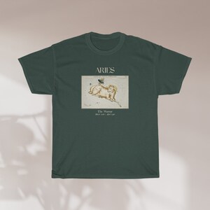 Pu&ograve; includere: Una maglietta verde scuro con una grafica bianca della costellazione dell'Ariete. La grafica include un ariete con una farfalla sulla schiena e il testo "Aries The Ram March 21 - April 19".