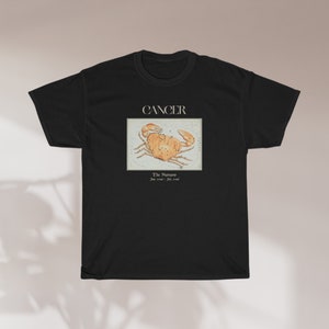 May include: Black t-shirt with a white graphic of the Cancer zodiac sign, a crab, with the text "Cancer" and "The  Numinous June 21st - July 22nd".