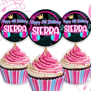May include: Three pink and blue cupcakes with black and neon pink cupcake toppers that say "Happy 8th Birthday Sierra" with a crown and headphones graphic.