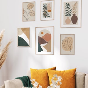 May include: A gallery wall with six framed prints featuring abstract line drawings of plants and landscapes in shades of brown, green, and orange. The prints are arranged in a symmetrical pattern on a white wall.
