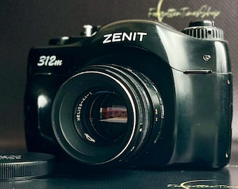 May include: Black Zenit 312m camera with a Helios-44-2 lens. The camera has white lettering and a lens cap is in the foreground. The camera is on a dark surface.