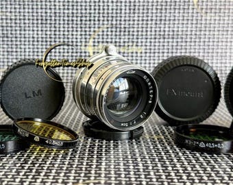 May include: A silver Jupiter-8 50mm f/2 camera lens positioned centrally, surrounded by four black circular lens caps labeled MICRO, LM, FX mount, and NEX. Four thin circular lens filters with 40.5x0.5 markings are arranged in the foreground.