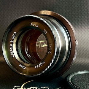 Op de afbeelding: Een vintage cameralens met een metallic afwerking. De lens heeft markeringen waaronder "F=300" en "1:10". De tekst "Made in USSR" is ook zichtbaar. De lens is een klassiek stuk fotografie-apparatuur.