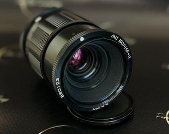 May include: A black MC Волна-9 880123 lens with a silver band and a black lens cap.