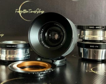 May include: A set of five camera lens adapters, including M42-NEX, M42-M4/3, M42-FX, and two additional adapters. The adapters are made of metal and have a silver finish. The lens adapters are used to connect different camera lenses to different camera bodies.