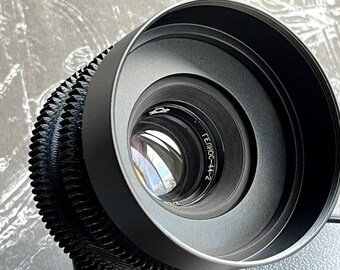 May include: A black camera lens with a silver ring and the text "ТЕЛМОС-44-2" printed on it.