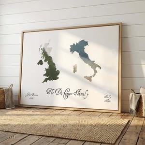 May include: A framed print showing watercolour maps of Great Britain and Italy. The text "The Di Campo Family" is centered below the maps, with "Great Britain" and "Italy" written below each map. The print is displayed in a room with a rug and baskets.