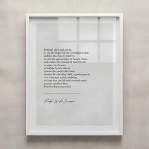May include: A framed print with a white border, featuring a quote by Ralph Waldo Emerson in a minimalist style. The text is in a simple, elegant font on a light gray background. The quote is about the meaning of success.