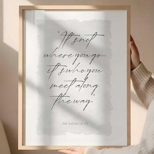 Puede incluir: Un cartel enmarcado con la cita "No es a dónde vas... es a quién conoces en el camino". El texto está escrito a mano, con "The Wizard of Oz" en la parte inferior. El marco es de madera clara.