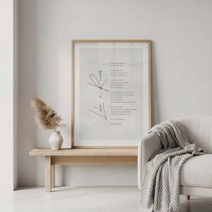 May include: A framed print with a poem in black script, titled "Life is". The artwork is displayed above a wooden bench with a vase of dried flowers. A white sofa with a gray knitted throw is to the right.