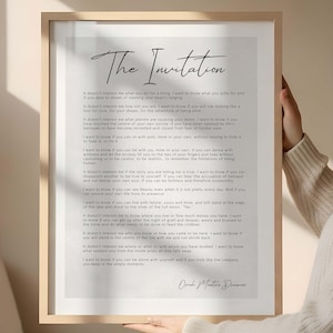 May include: A framed print with the title "The Invitation" in elegant script. The print features a poem with a handwritten signature at the bottom. The frame is a light wood colour.