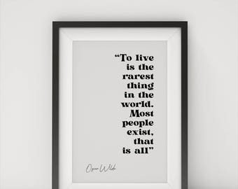 May include: A framed print with a black frame and a white background. The print features a quote by Oscar Wilde in black text: "To live is the rarest thing in the world. Most people exist, that is all."