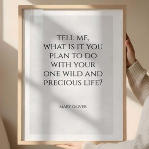 May include: A framed print featuring the quote "TELL ME, WHAT IS IT YOU PLAN TO DO WITH YOUR ONE WILD AND PRECIOUS LIFE?" by Mary Oliver. The text is black on white, in a light wood frame.
