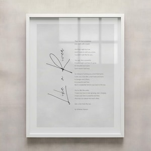 May include: A framed print with a white border features a poem with the words "Love" and "Like a river finds the sea" in black script. The poem is on a light gray background.