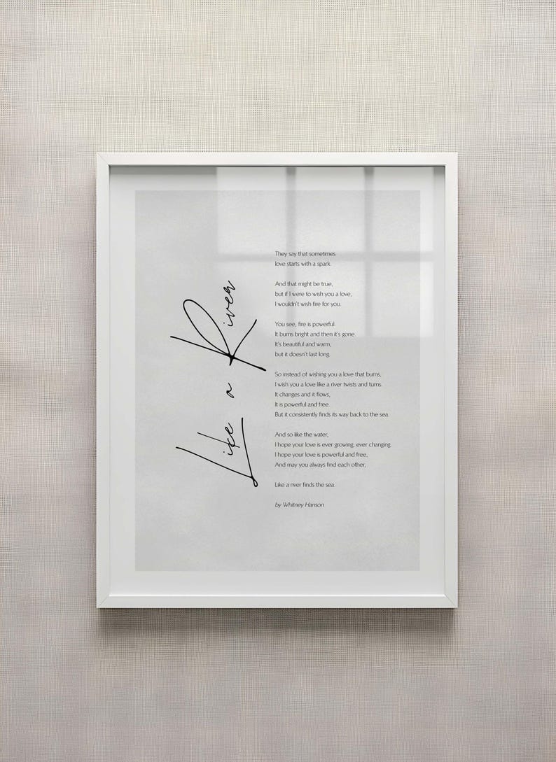May include: A framed print with a white border features a poem with the words "Love" and "Like a river finds the sea" in black script. The poem is on a light gray background.