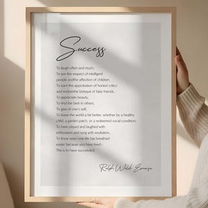 May include: A framed print with the word "Success" in script, and a quote by Ralph Waldo Emerson. The black text is on a white background, within a light wood frame. A motivational piece for home decor, suitable for any room.