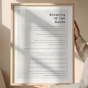 May include: A framed print with the text "Blessing of the Hands" in a black font. The print features a poem about love and support. The frame is a light wood colour.