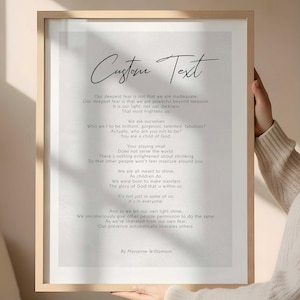 Könnte beinhalten: Gerahmter Druck mit dem Text "Custom Text" oben. Der Druck zeigt ein Gedicht von Marianne Williamson in einer einfachen, eleganten Schriftart. Der Rahmen ist helles Holz.