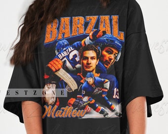 Op de afbeelding: Zwart oversized T-shirt met een vintage grafische print van een hockeyer die een blauw en oranje shirt draagt met de naam "Barzal" en het nummer "13" op de rug. De tekst "Mathew" is onder de afbeelding gedrukt.