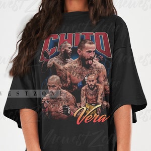 Puede incluir: Camiseta negra de gran tamaño con un gráfico de estilo vintage de un luchador de artes marciales mixtas, "Chito Vera", en una pose de lucha. El gráfico es de color rojo, amarillo y azul.