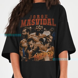 Puede incluir: Camiseta negra de gran tamaño con un estampado gráfico de estilo vintage que presenta una foto de Jorge Masvidal y el texto "Jorge Masvidal Gamebred".
