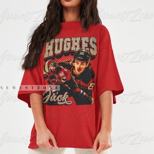 May include: Red oversized t-shirt with a vintage graphic print of a hockey player wearing a red and white jersey with the name "Hughes" and the number "86" on the back. The text "Jack" is printed below the graphic.
