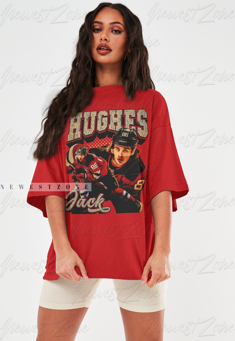 May include: Red oversized t-shirt with a vintage graphic print of a hockey player wearing a red and white jersey with the name "Hughes" and the number "86" on the back. The text "Jack" is printed below the graphic.