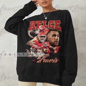 May include: Black long-sleeve sweatshirt with a vintage-style graphic print of a football player wearing a red jersey with the name "KELCE" and the number "87" printed on it. The text "Travis" is printed below the graphic.