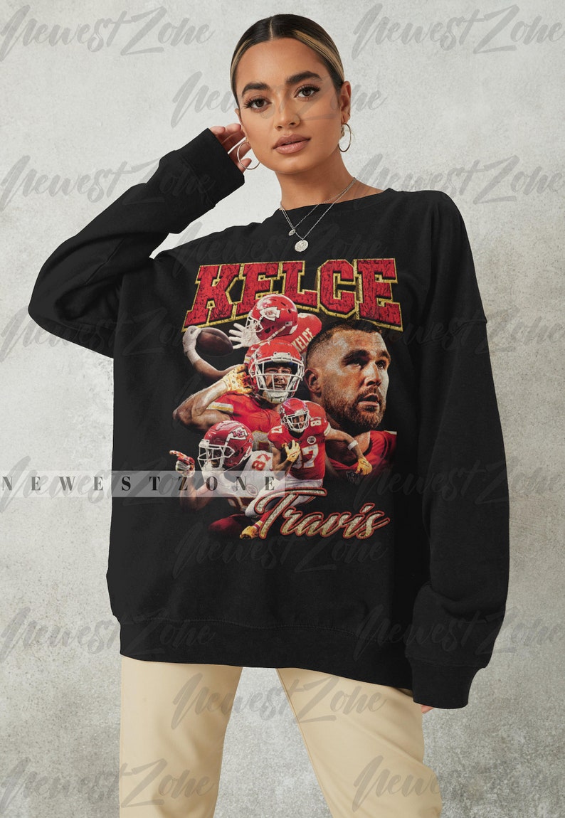 May include: Black long-sleeve sweatshirt with a vintage-style graphic print of a football player wearing a red jersey with the name "KELCE" and the number "87" printed on it. The text "Travis" is printed below the graphic.