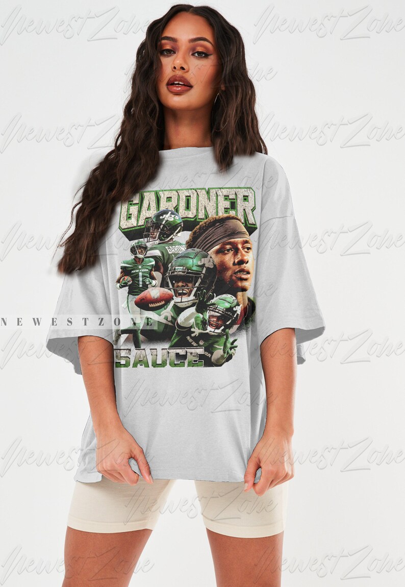 May include: An oversized grey t-shirt featuring a graphic print of a football player wearing a green and white jersey with the text "GARDNER" and "SAUCE".